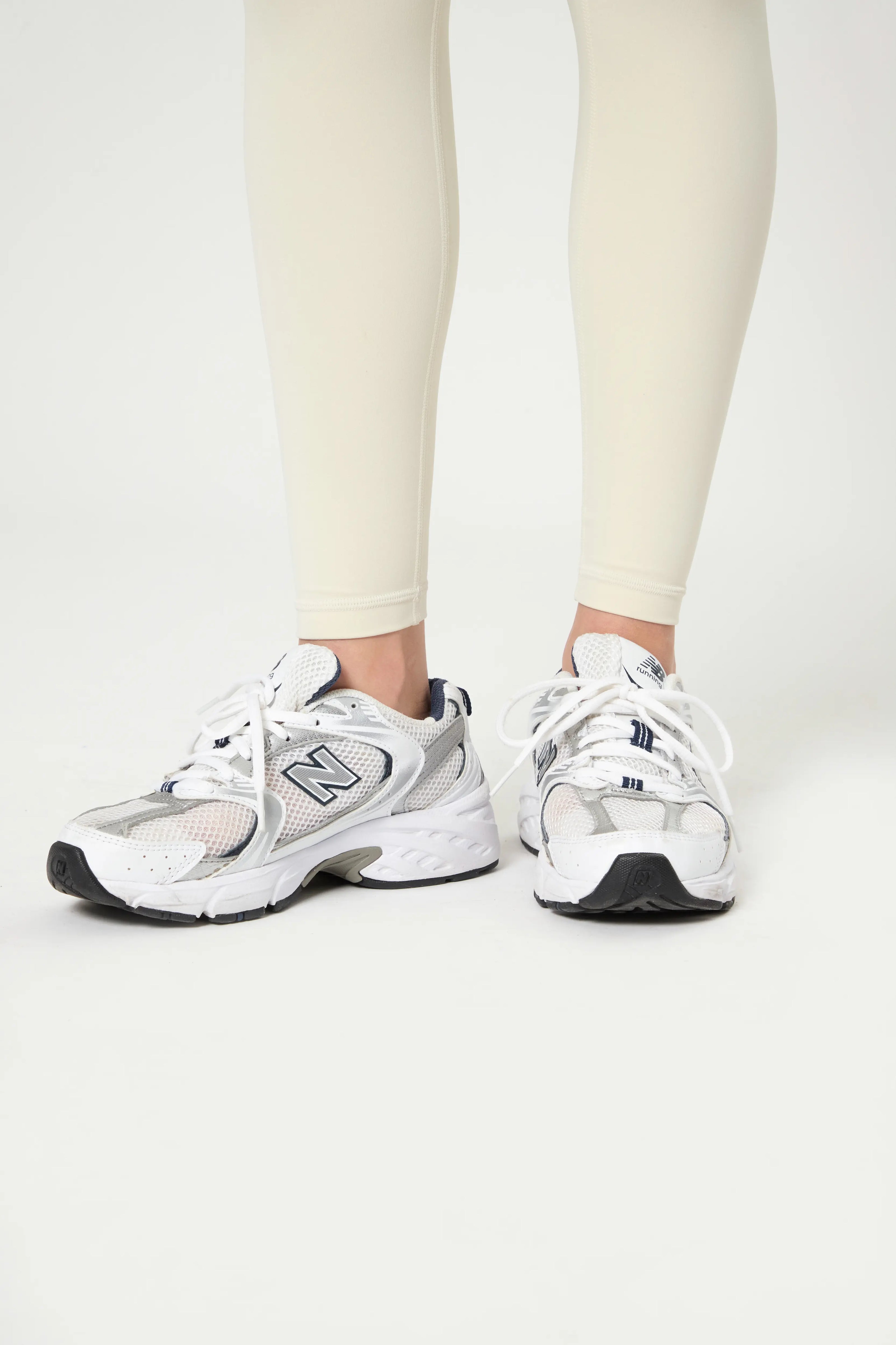 Базові легінси молочного кольору shown on model wearing white sneakers, highlighting high waistband and smooth fit.