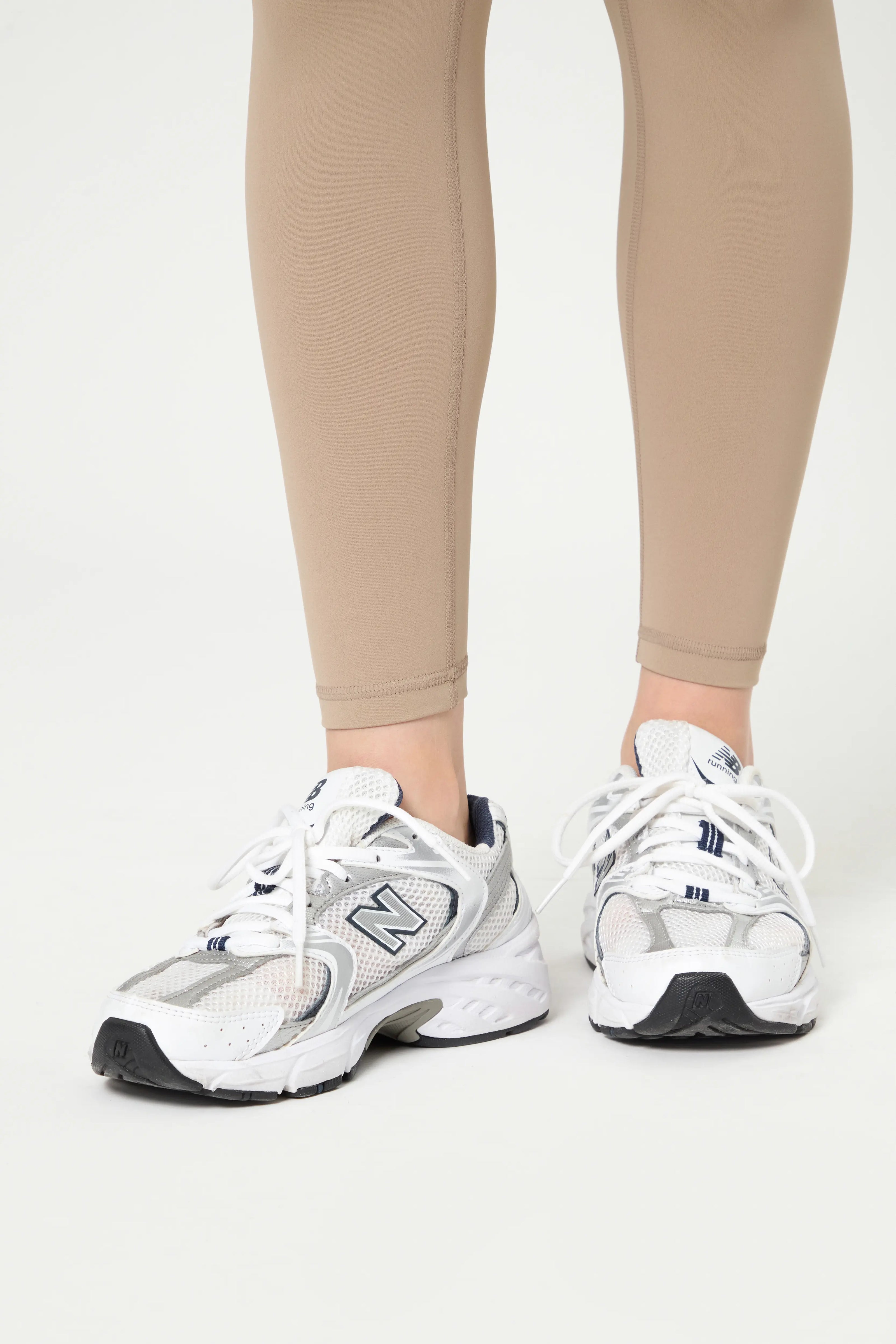Базові легінси кавового кольору close-up on lower legs with white sneakers on white background