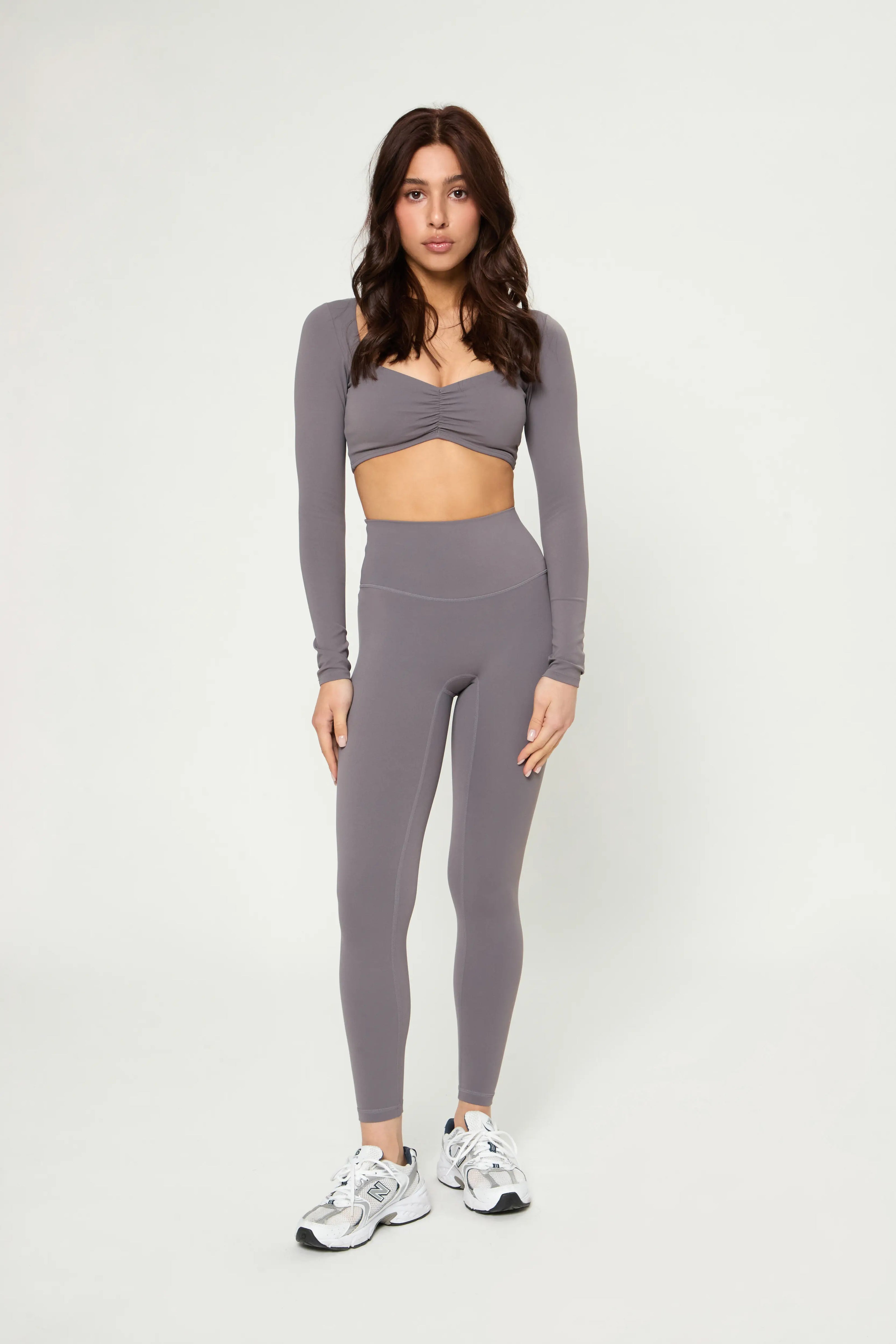 Woman wearing Базові легінси кольору графіт high-waisted seamless leggings with wide waistband and athletic shoes.
