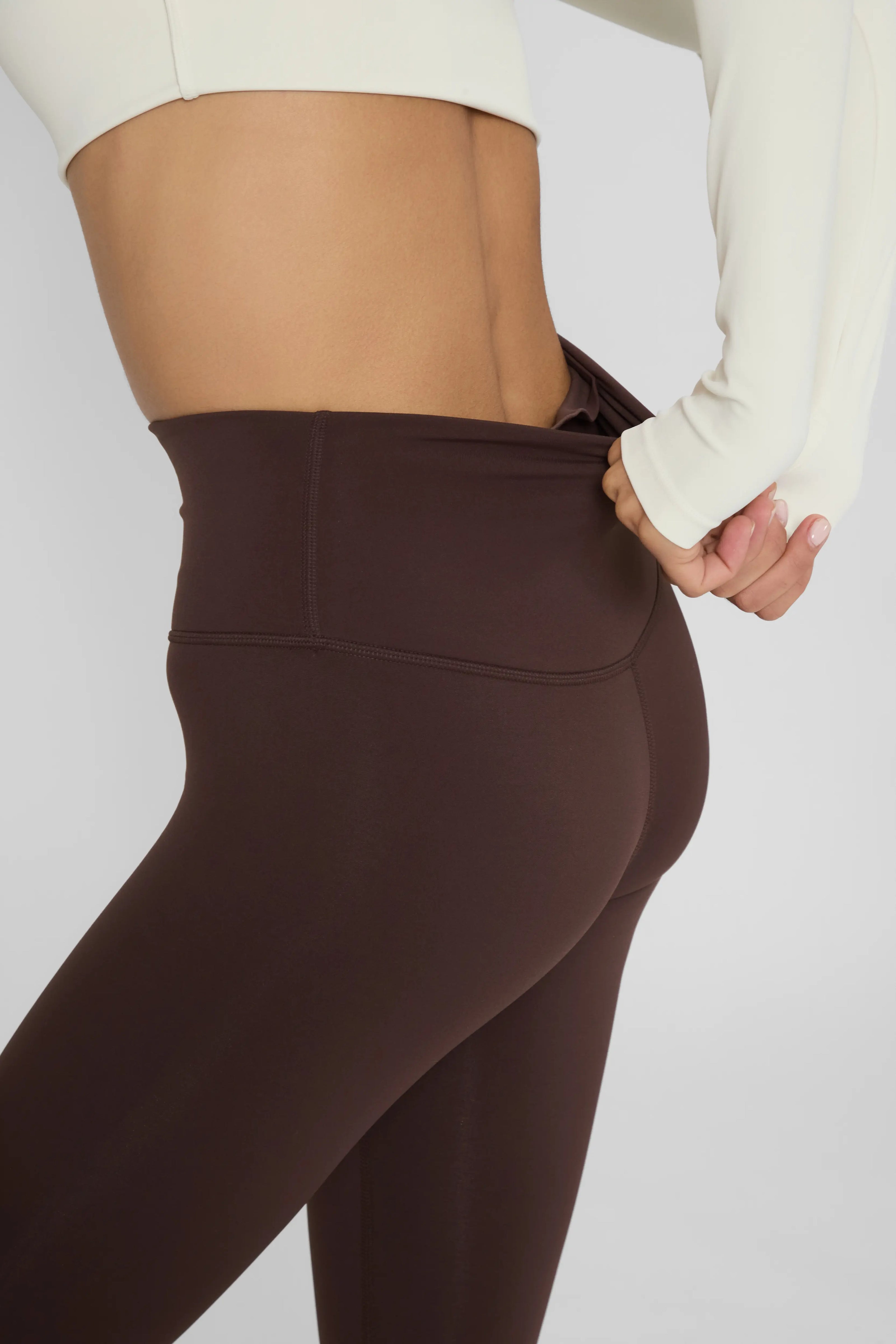Утеплені базові легінси з начосом коричневого кольору, крупний план поясу зі злегка розтягнутої тканини ззаду