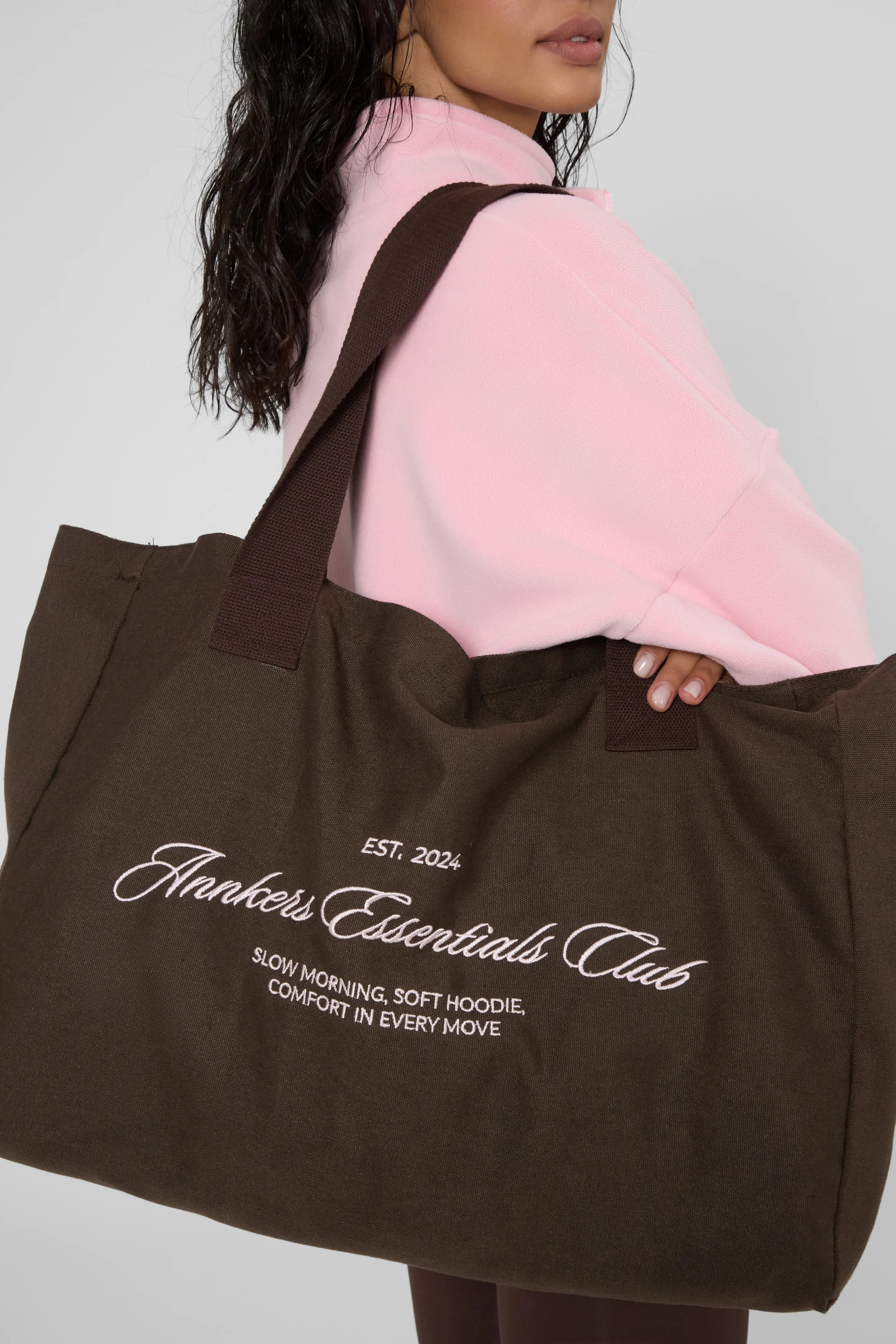 Утеплені базові легінси з начосом коричневого кольору, близький план тканини та фактури на моделі в рожевому светрі