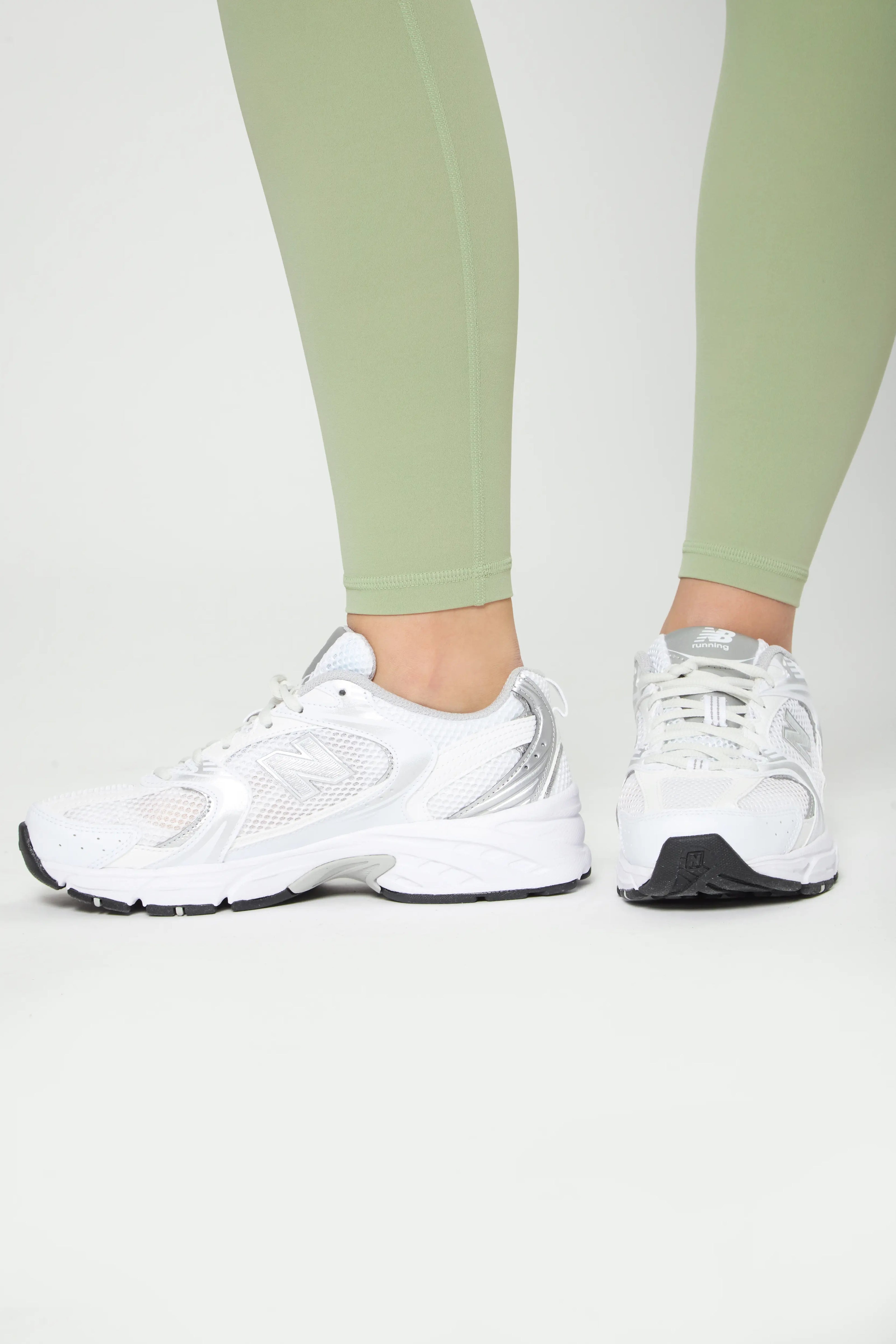 Close-up of legs wearing olive Basic Leggings with white sneakers, showcasing comfort and sleek design.